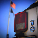 Red taillight of a vehicle with 'Airborne' insignia on a blue sky background