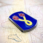 196th Infantry Brigade Metal Emblem with a yellow infinity symbol and red flame-like accents, photographed on an old map background.