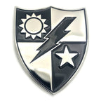 A shield-shaped enamel pin or badge with a polished silver border and black-and-silver divided design featuring a sun, lightning bolt, and star.
