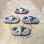 Four silver Parachutist Badge Jump Wings Metal Decals on a textured surface with wings and a parachute on an old map background