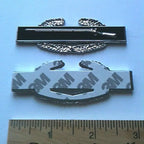 Combat Infantryman Badge Metal Car Decal First Award with 3M tape and a ruler for scale on a light blue background