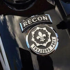 Chrome 'RECON' and 'TOUJOURS PRET' emblem on a dark background