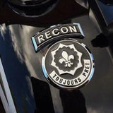 Chrome 'RECON' and 'TOUJOURS PRET' emblem on a dark background