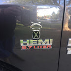 A chrome plated, zinc alloy Military Police Corps Insignia with a cross pistols design, attached to a vehicle.