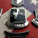 502nd Infantry Regiment Strike Metal Auto Emblem on an american flag background with 4 other badges partially in view