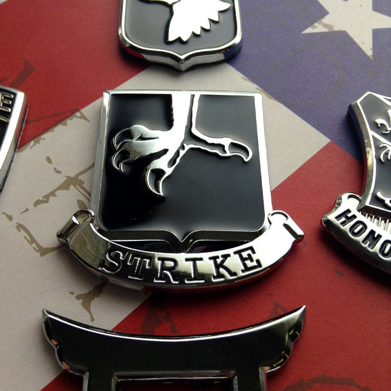 502nd Infantry Regiment Strike Metal Auto Emblem on an american flag background with 4 other badges partially in view
