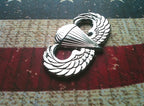 Chrome Parachutist Badge “Jump Wings” Metal Car Emblem angled to the left on a red, white and blue background